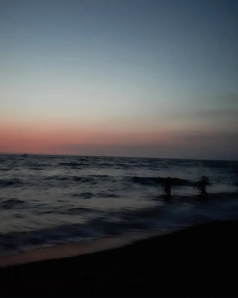 Waves at a beach under a fading blue and pink sky